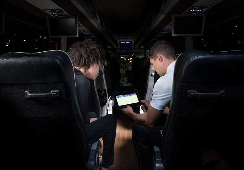 Two men view soccer video on coach