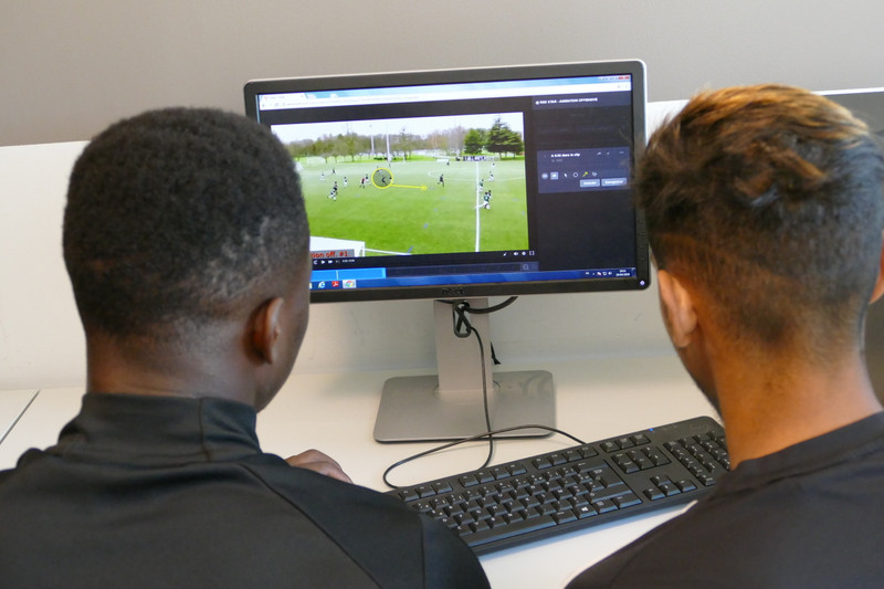 Dos jugadores analizan el juego de un video de fútbol en el monitor