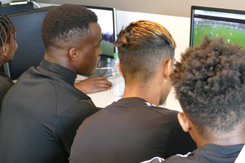Football team watching video replays on laptop