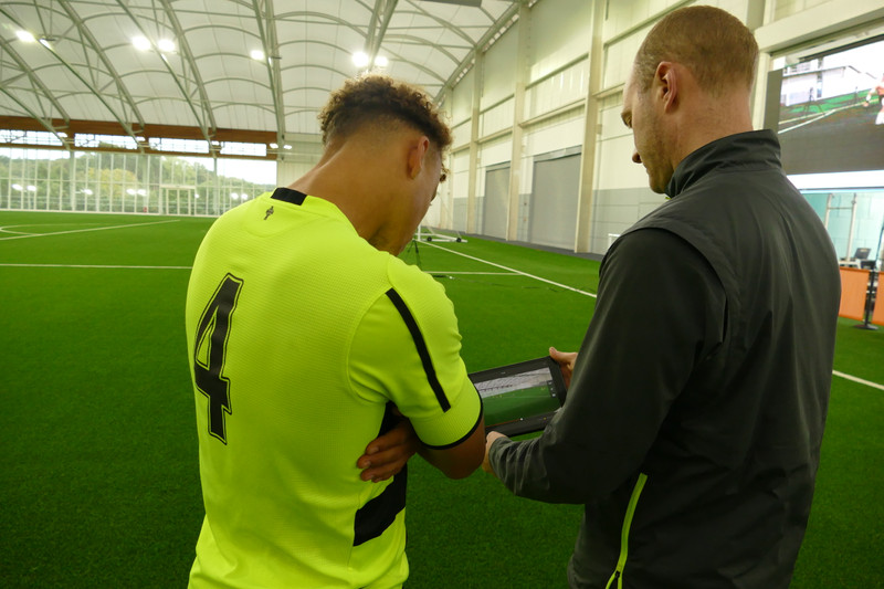 El entrenador muestra a un jugador repeticiones de video en la práctica de fútbol