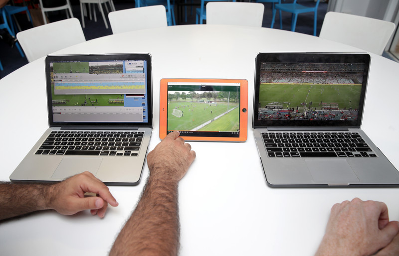 Two men watching soccer footage on laptops and tablet